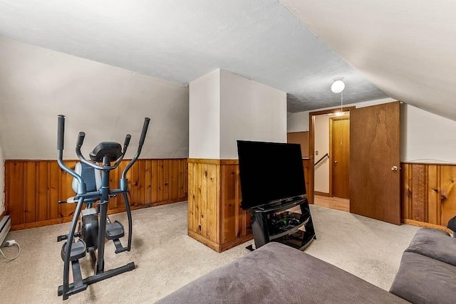 exercise area with lofted ceiling, wainscoting, light colored carpet, and wooden walls