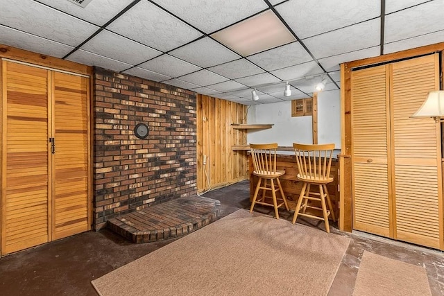 bar with a drop ceiling, wooden walls, and a bar