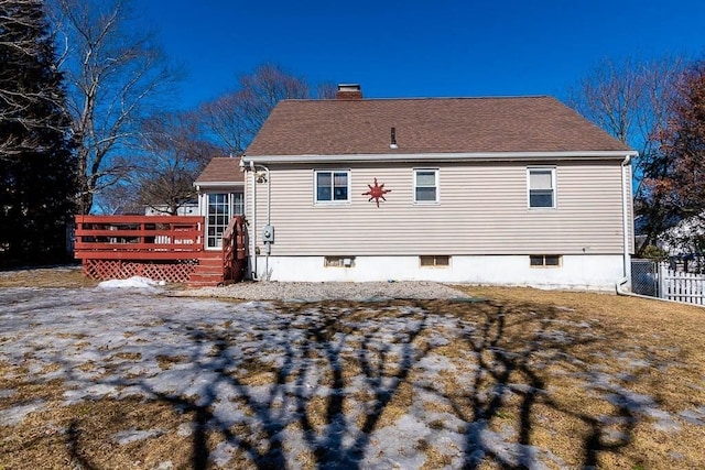 rear view of house with a shingled roof, a chimney, fence, and a wooden deck