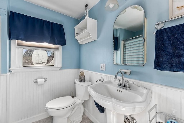 bathroom with toilet, a sink, and wainscoting