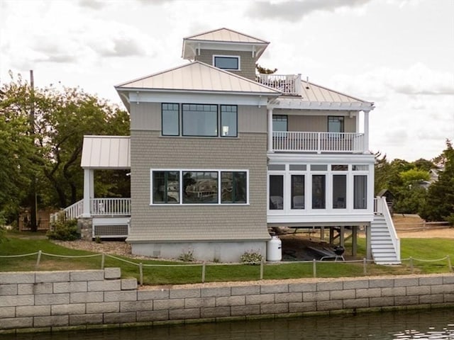 rear view of property with metal roof, a yard, a standing seam roof, and a balcony