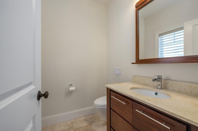 half bath featuring toilet, tile patterned floors, vanity, and baseboards