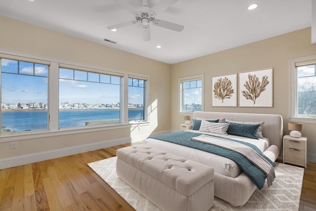 bedroom with wood finished floors, visible vents, baseboards, and multiple windows