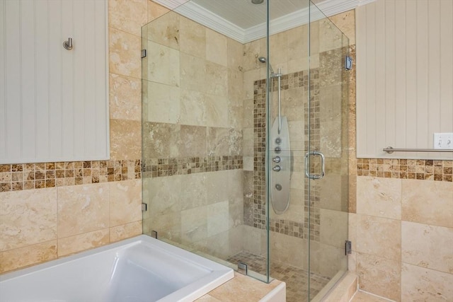 bathroom with a stall shower, a garden tub, tile walls, and crown molding