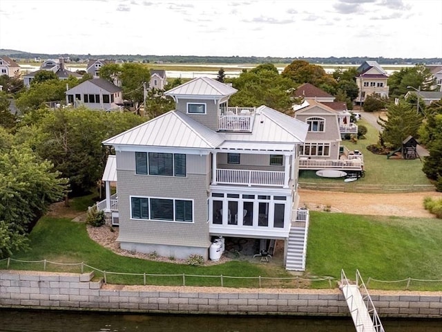 rear view of house with metal roof, a balcony, stairs, a yard, and a standing seam roof