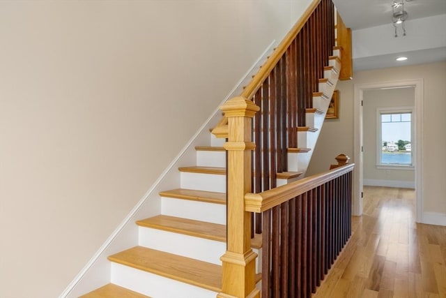 stairway featuring recessed lighting, wood finished floors, and baseboards