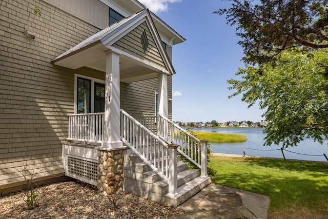 doorway to property with a water view, a porch, and a yard