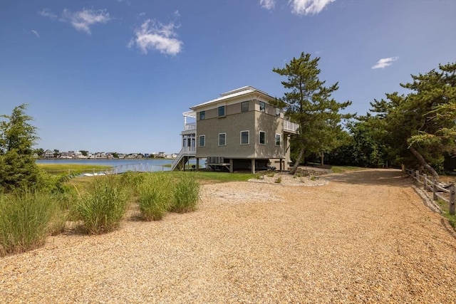 back of property with a water view and stairway