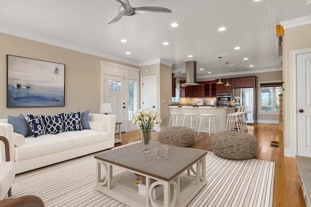 living area featuring ceiling fan, recessed lighting, light wood-type flooring, and crown molding