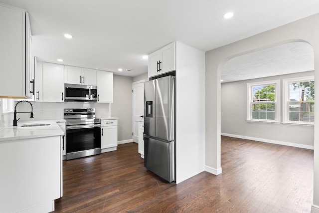 9 Bishop Rd, Quincy, MA 02170 - kitchen featuring stainless steel appliances, a sink, arched walkways, dark wood-style floors, and light countertops