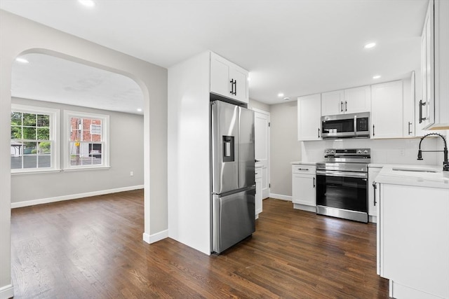 9 Bishop Rd, Quincy, MA 02170 - kitchen with appliances with stainless steel finishes, a sink, arched walkways, dark wood-style floors, and light countertops