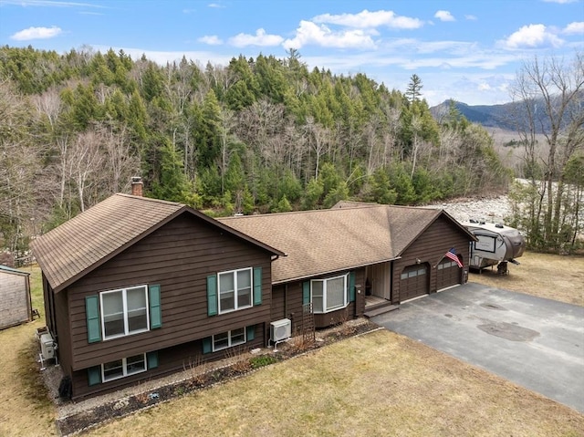 113 Glen Rd, Gorham, NH 03581 - view of front facade with a garage, asphalt driveway, a mountain view, a chimney, and a wooded view