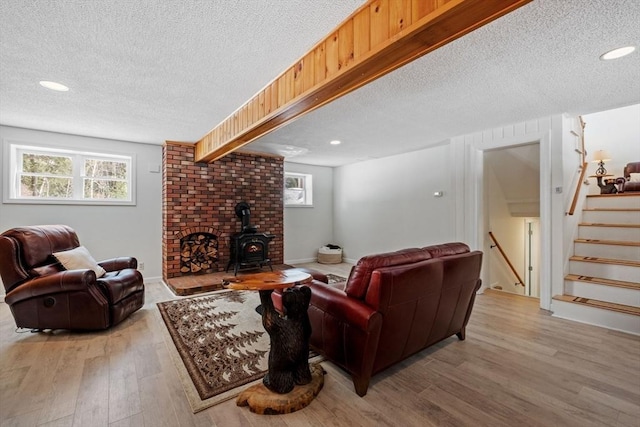 113 Glen Rd, Gorham, NH 03581 - living room featuring a textured ceiling, light wood-style flooring, a wood stove, healthy amount of natural light, and stairs