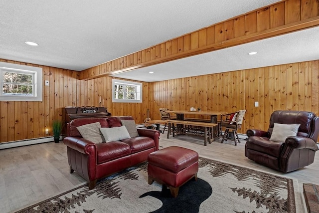 113 Glen Rd, Gorham, NH 03581 - living room with healthy amount of natural light, wood finished floors, a textured ceiling, wooden walls, and a baseboard radiator