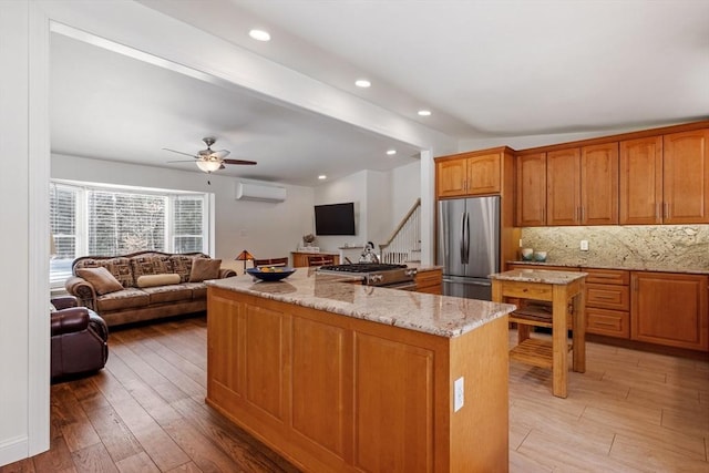 113 Glen Rd, Gorham, NH 03581 - kitchen with appliances with stainless steel finishes, a wall mounted air conditioner, a kitchen island, open floor plan, and light stone counters