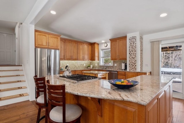 113 Glen Rd, Gorham, NH 03581 - kitchen with appliances with stainless steel finishes, a large island, light wood-style floors, light stone countertops, and decorative backsplash