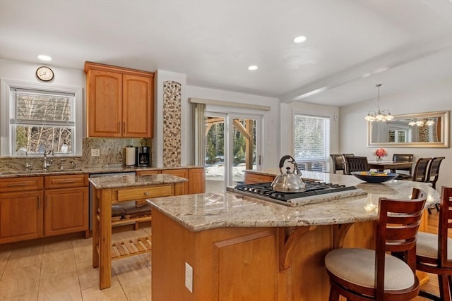 113 Glen Rd, Gorham, NH 03581 - kitchen with stainless steel gas stovetop, a sink, a kitchen island, light stone countertops, and a kitchen bar