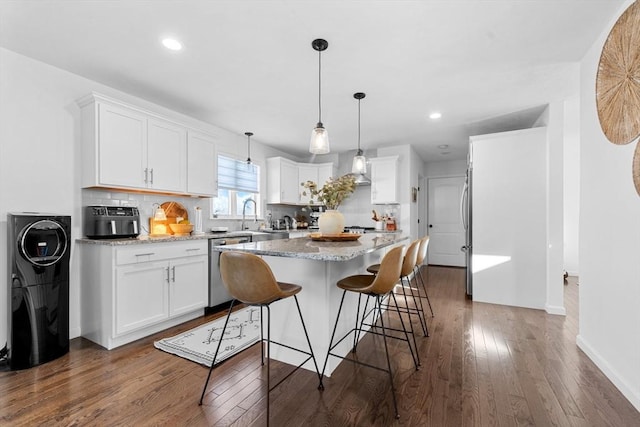 11 Wedge Dr, Lakeville, MA 02347 - kitchen featuring appliances with stainless steel finishes, dark wood-type flooring, white cabinetry, a center island, and backsplash