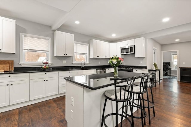 kitchen featuring a kitchen island, plenty of natural light, white cabinetry, and appliances with stainless steel finishes