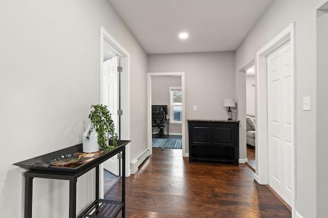 hall with a baseboard heating unit and dark hardwood / wood-style floors