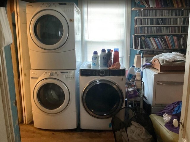 laundry area with stacked washer / drying machine and wood finished floors