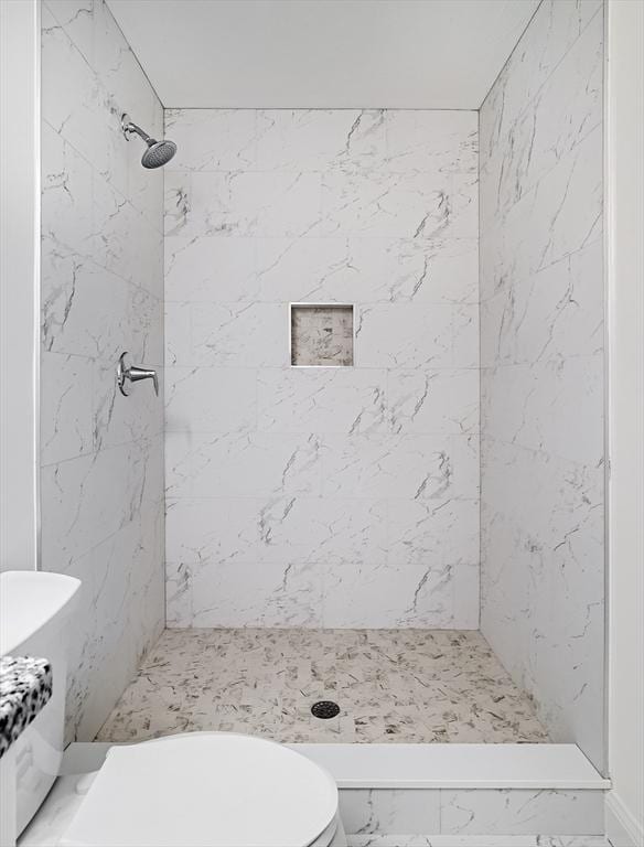 bathroom with a tile shower and toilet