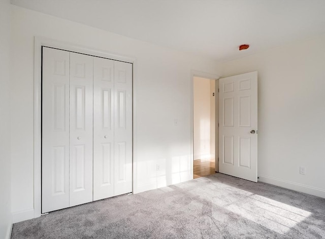 unfurnished bedroom featuring light colored carpet and a closet