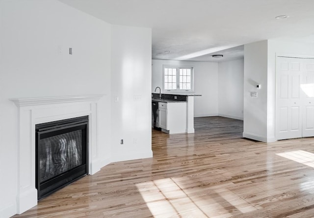 unfurnished living room featuring sink and light wood-type flooring