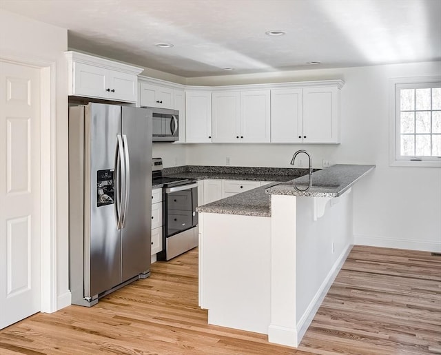 kitchen featuring light wood-type flooring, white cabinetry, kitchen peninsula, and appliances with stainless steel finishes