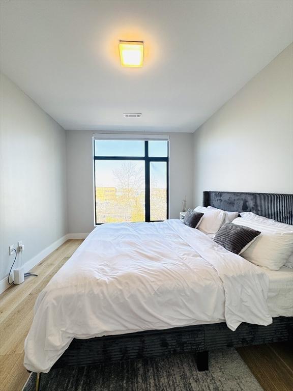 bedroom with visible vents, baseboards, and wood finished floors