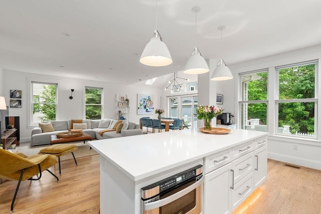 323 Lake Ave Unit 323, Newton, MA 02461 - kitchen featuring stainless steel oven, light wood-style floors, white cabinets, a kitchen island, and light countertops
