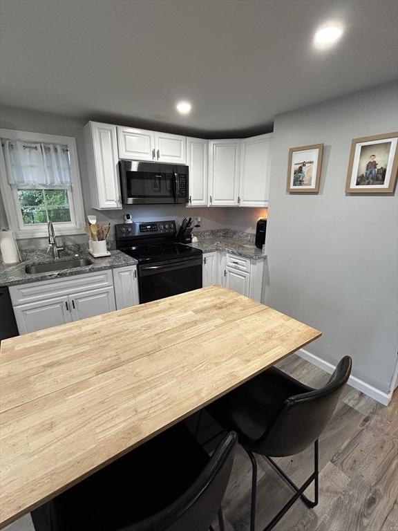 1 Sunderland Ter, Worcester, MA 01604 - kitchen featuring black range with electric stovetop, wood finished floors, a kitchen breakfast bar, white cabinetry, and recessed lighting