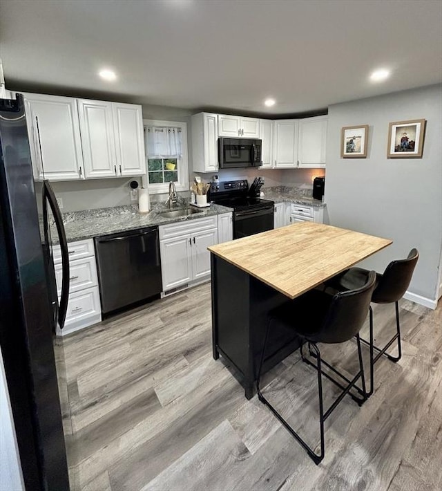 1 Sunderland Ter, Worcester, MA 01604 - kitchen featuring black appliances, light wood-style flooring, white cabinetry, recessed lighting, and light stone countertops