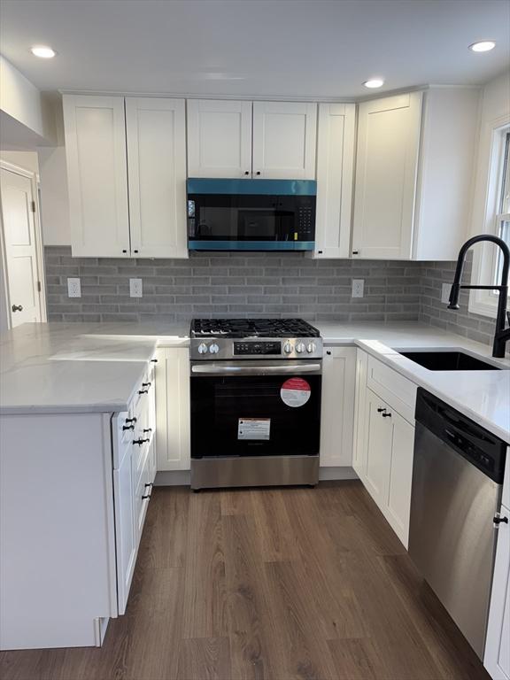 kitchen with tasteful backsplash, sink, white cabinets, and appliances with stainless steel finishes