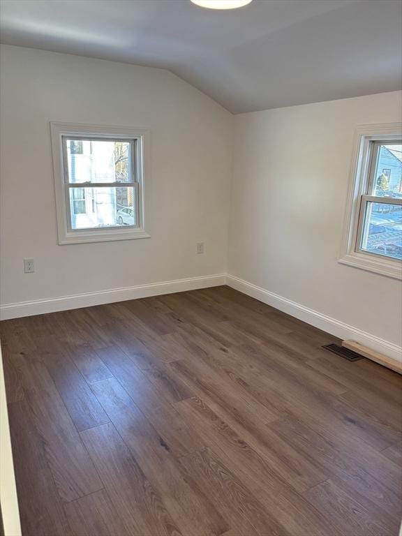 empty room featuring dark wood-type flooring and vaulted ceiling