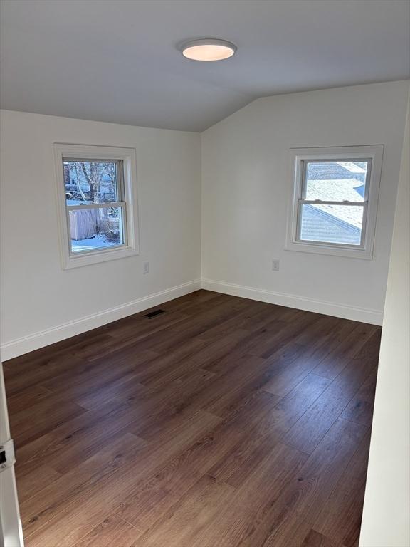 spare room with vaulted ceiling and dark hardwood / wood-style flooring