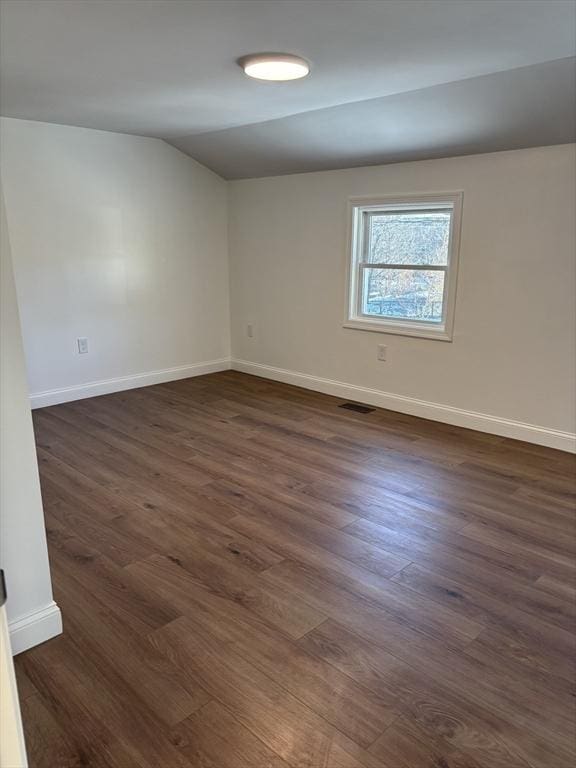 spare room featuring dark hardwood / wood-style flooring and vaulted ceiling