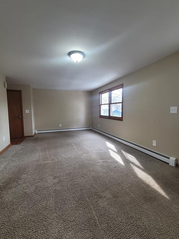 carpeted spare room featuring a baseboard radiator and baseboards