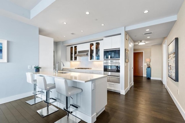 kitchen with sink, a breakfast bar area, appliances with stainless steel finishes, an island with sink, and white cabinets