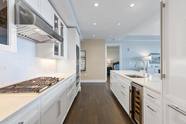 kitchen with white cabinetry, beverage cooler, and exhaust hood