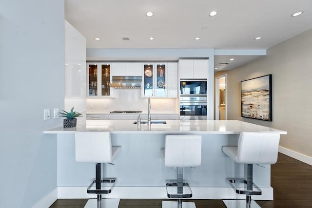 kitchen with kitchen peninsula, sink, a breakfast bar area, and white cabinets