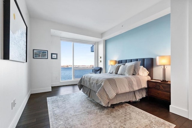 bedroom featuring a water view, access to exterior, and dark wood-type flooring