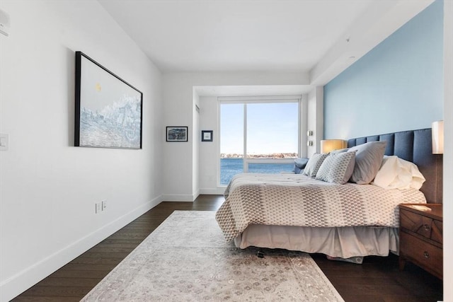 bedroom featuring dark hardwood / wood-style floors and a water view