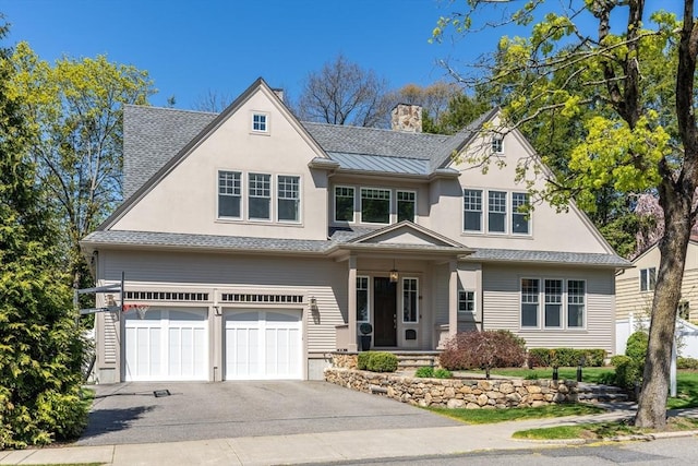 view of front facade with a garage, aphalt driveway, stucco siding, a chimney, and a standing seam roof