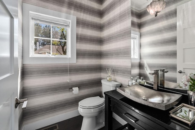 half bath featuring toilet, wallpapered walls, and a healthy amount of sunlight
