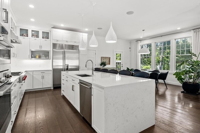kitchen with a sink, appliances with stainless steel finishes, dark wood-style floors, and ornamental molding