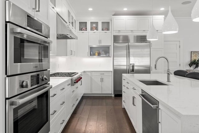 kitchen with a sink, under cabinet range hood, white cabinets, and stainless steel appliances