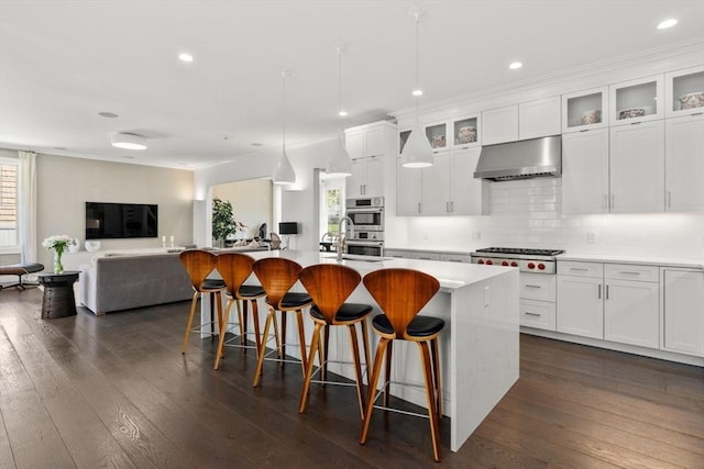 kitchen featuring a breakfast bar area, ventilation hood, open floor plan, stainless steel appliances, and dark wood-type flooring