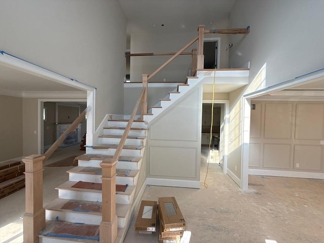 stairs with ornamental molding and a towering ceiling