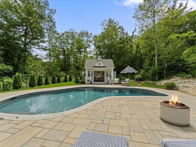 35 Forster Rd, Manchester, MA 01944 - swimming pool with an exterior structure, a patio area, an outdoor structure, a fire pit, and view of wooded area